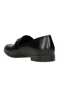 Černá kožená nazouvací bota s kulatou špičkou, s prošitým designem a malým, nízkým podpatkem. Hladký povrch a minimální kovové doplňky.