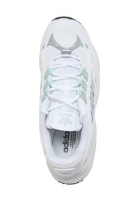 Bijela atletska tenisica s mrežastim i sintetičkim gornjim dijelom, srebrnim detaljima i svijetloplavim jezikom. Ima vezice i podstavljeni potplat za podršku.