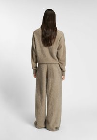 Mjuk beige lounge-set i fluffigt tyg; har en avslappnad passform med rundad halsringning och vida byxor med texturerad yta.