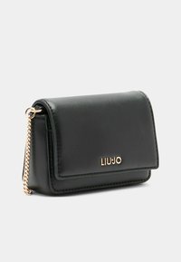 Portafoglio in pelle sintetica nera con chiusura a pattina, branding in tonalità oro e tracolla a catena. Texture liscia con bordi cuciti e design compatto.