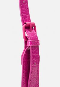 Bracciale in finta pelle di colore rosa brillante con texture a coccodrillo. Presenta una fibbia in plastica e dettagli di cucitura lungo i bordi.