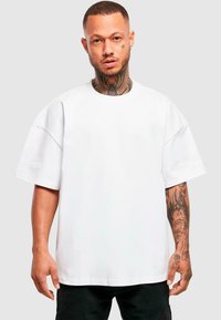 Balta per didelė t-shirt su trumpomis rankovėmis, pagaminta iš medvilnės. Sukurtas apvalus kaklo iškirpimas ir laisvas kirpimas. Matinė tekstūra, minimalistinis dizainas.