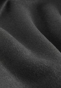 Mörkgrått tyg med en mjuk, slät textur, med försiktiga veck och subtila reflexer som visar dess formbara och plyschiga natur.