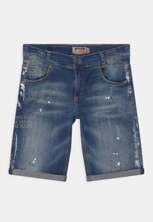 Blue denim shorts with rolled cuffs, front pockets, faded and distressed areas, and printed text on both legs.