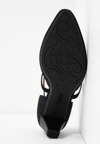 Scarpa con tacco alto in suede nero, con punta affusolata e suola in gomma caratterizzata da un motivo a spirale. Il marchio "Gabor" è visibile sulla suola.