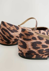 Chaussures à motif léopard avec un talon bas et arrondi, extérieur en tissu, et une bride à l'arrière. Le schéma de couleurs présente des taches marron et noires.