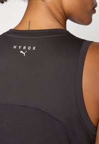 Schwarzes Sport-Top aus atmungsaktivem Material mit HYROX-Logo und PUMA-Branding. Es hat eine glatte Textur, ärmelloses Design und einen runden Ausschnitt.