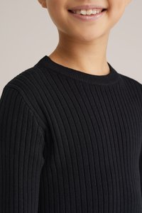 Svart ribbad stickad tröja med rund halsringning och långa ärmar, som framhäver ett strukturerat tyg med vertikala ränder.