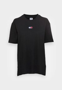 T-shirt en coton noir à manches courtes, col rond, avec un petit patch logo multicolore sur la poitrine. Texture douce, coupe décontractée.
