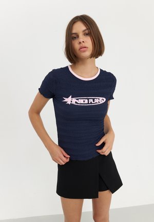 Navy blue textured T-shirt with short sleeves, featuring a pink crew neckline and "NO PLANS" graphic on the front. Black shorts with a folded design.