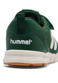 Groene sneaker met een gestructureerd leren en mesh bovenwerk, witte branding, gevoerde kraag, en een flexibele rubberen zool met een lichtbruine buitenzool.