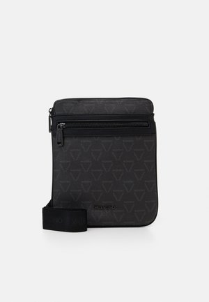 Bolso negro tipo bandolera hecho de cuero texturizado. Cuenta con un compartimento principal con cremallera, patrón de logotipo y una correa ajustable con branding.