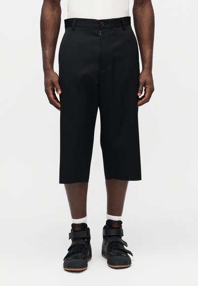 Pantalon noir court en tissu lisse, avec fermeture à boutons sur le devant, poches latérales et design épuré.