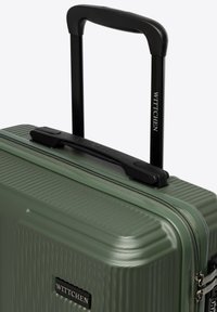 Zelený tvrdý kufr s roztažitelnou černou teleskopickou rukojetí a horní rukojetí pro nošení, s názvem značky "Wittchen" na rukojeti a na těle kufru.