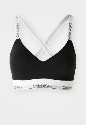 Zwarte bralette met V-hals en kruisrugontwerp. Bevat witte merkbandjes en een witte band met het "Calvin Klein" logo. Gladde textuur.