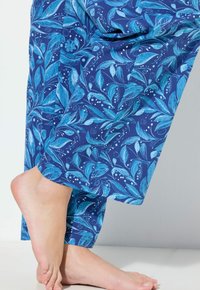 Katoenen pyjamabroek met een marineblauwe achtergrond en een blauw bladerenpatroon, verkorte lengte, gladde textuur en een relaxte pasvorm.