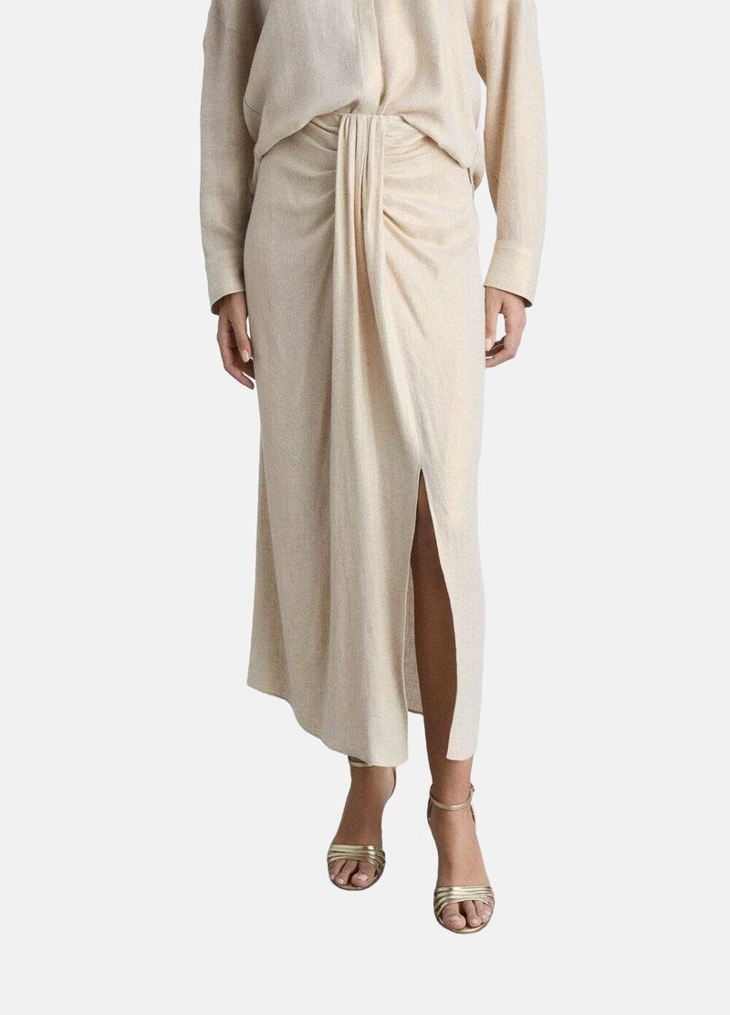 Beige midi-rok van zachte stof; met een voorsprong en geplooide details bij de taille. Gepaard met metallic gouden sandalen met bandjes.