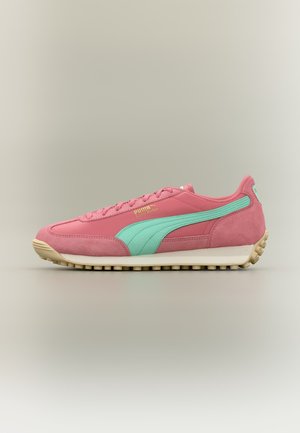 Rózsaszín Puma Easy Rider sportcipő türkiz csíkkal, bézs talppal és texturált talpbetéttel, oldalnézetből, semleges háttér előtt.