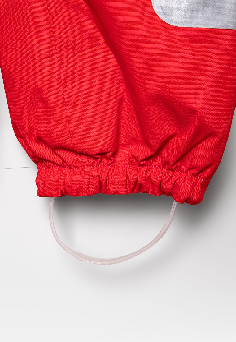 Manga de tela roja con puño elástico y correa blanca unida, probablemente parte de una prenda protectora o de trabajo.