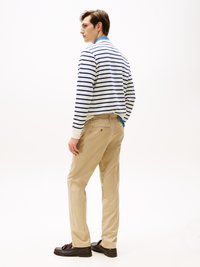 Gestreifter Pullover in Weiß und Marineblau, hellblauer Kragen; khakifarbene Hose mit Gesäßtasche; dunkelbraune Slipper. Glattes Material, lässige Passform.