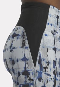 Leggings de deporte de cintura alta en negro con un patrón abstracto en tonos azul-gris. Presentan costuras planas y un tejido texturizado para mayor comodidad.