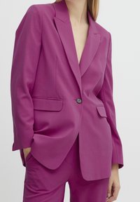Fuchsia blazer med notchad slag, enkelknäppning och framfickor. Slät textur, skräddarsydd passform med långa ärmar.