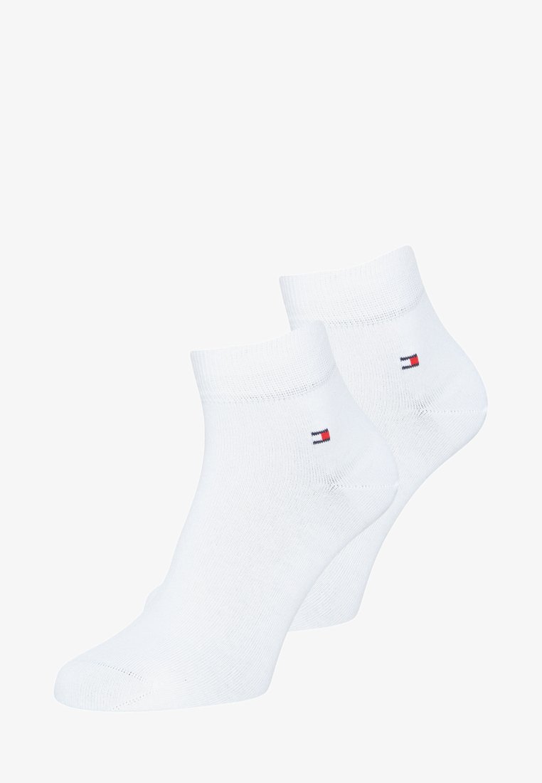 Meias brancas de tornozelo feitas de uma mistura de algodão; apresentam um pequeno logótipo vermelho, branco e azul na lateral. Textura suave com punhos canelados.