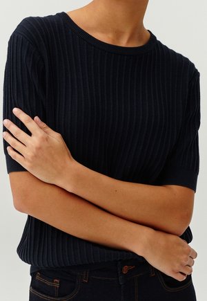 Maglione a coste navy con scollo rotondo e maniche corte. Tessuto morbido, vestibilità comoda e accentuato da un sottile motivo a coste.