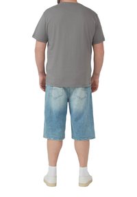 Graues T-Shirt, lockere Passform, kombiniert mit hellblauen Jeansshorts. Weiße Socken und Schuhe runden das Outfit ab. Die Rückansicht zeigt die Details des Kleidungsstücks.