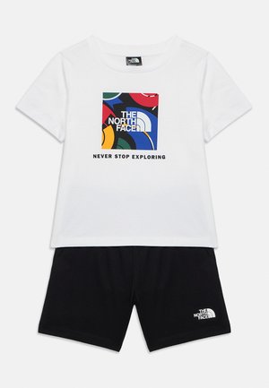 Weißes T-Shirt mit kurzen Ärmeln, einem bunten The North Face Logo und dem Schriftzug "Never Stop Exploring", kombiniert mit schwarzen Shorts, die ein kleines weißes Logo tragen.
