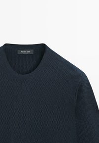 Maglione in maglia blu navy scuro con collo rotondo, caratterizzato da tessuto strutturato e un'etichetta "Massimo Dutti". Non presenta elementi metallici visibili né motivi.