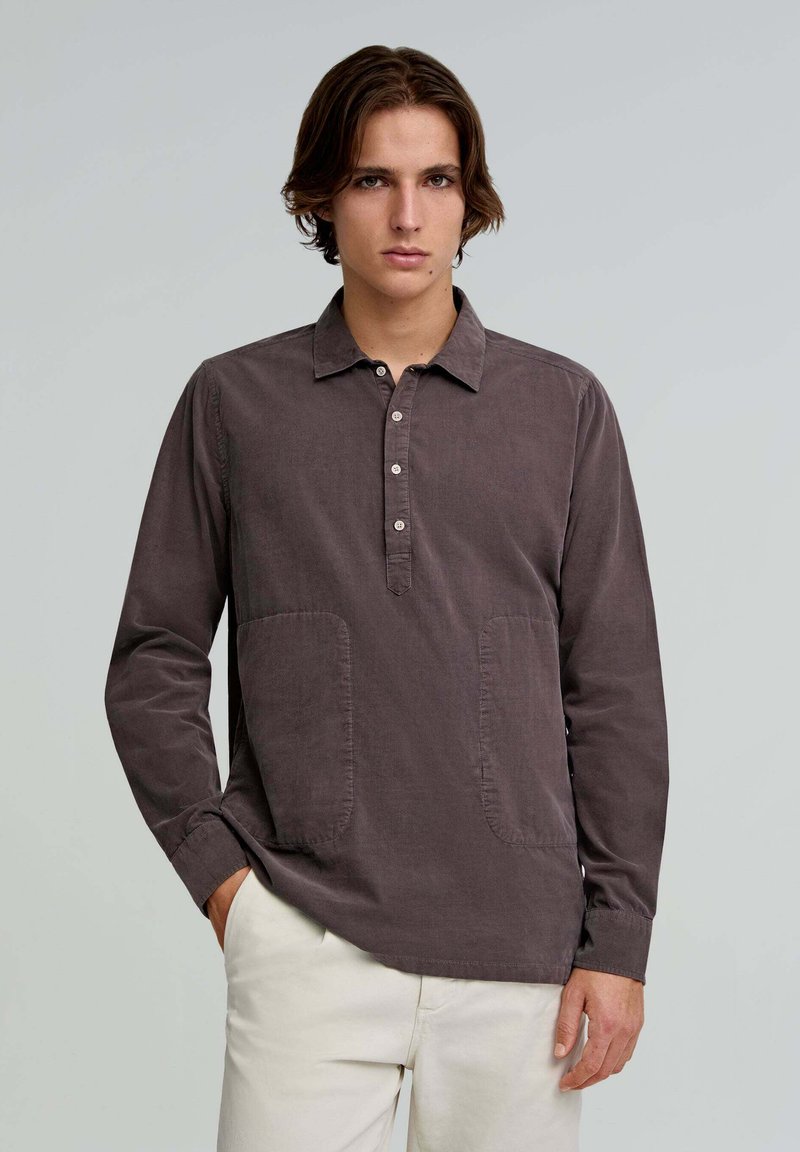 Long-sleeve shirt in dark gray fabric, featuring a buttoned placket, two front pockets, and a relaxed fit. Smooth texture with a collar.