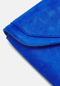 Clutch azul de ante con una textura suave, que presenta una solapa plegada y costuras en contraste a lo largo de los bordes.