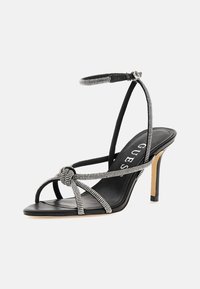 Svart högklackad sandal med rhinestone-accenter, med en remdesign, tunn ankelrem och en slät lädersula.