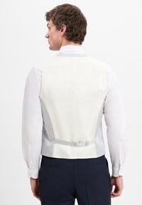 Weißer formeller Weste mit grauen Akzenten und verstellbarem Riemen hinten. Glattes Material und taillierte Passform, getragen über einem weißen Hemd.