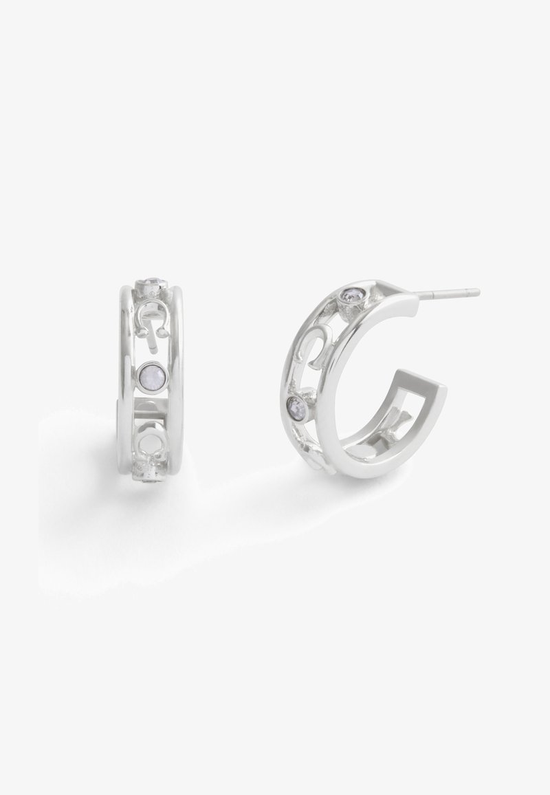 Sølvøreringe har et åbent design med cirkulære detaljer og små indlejrede ædelstene, der præsenterer en moderne og detaljeret stil.