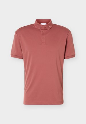 Kort mouw polo in poederroze met een drieknops sluiting en een klein logo borduursel op de kraag tegen een lichte achtergrond.