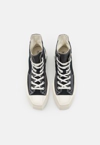 Zapatillas altas de lona azul marino con cordones blancos, que presentan un diseño texturizado y una puntera y suela de goma blanca en contraste.