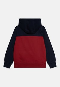 Felpa con cappuccio caratterizzata da corpo rosso e maniche blu scuro. Tessuto morbido con polsini e orlo a coste, che mostra un design a blocchi di colore.