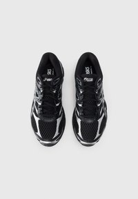Black mesh running shoes with silver accents, featuring a rounded toe box, lace-up design, and textured surface for grip.