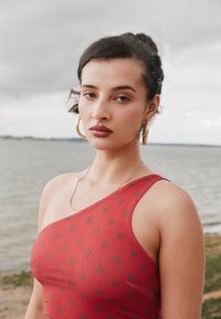 Piros pöttyös egyrészes vállpántos felső áttetsző anyagból. Finom aranylánc nyaklánccal és nagy karika fülbevalókkal kiegészítve.