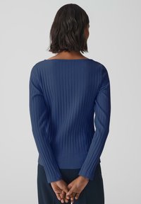 Navy ribbed long-sleeve top, featuring a wide neckline and fitted design. The texture is smooth with vertical stripes, creating a structured look.