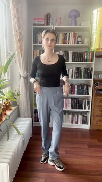 Svetlo modre visokotopne hlače z stranskimi žepi in enojnim gumbom, v kombinaciji z črnim dolgim topom in večbarvnimi športnimi copati.