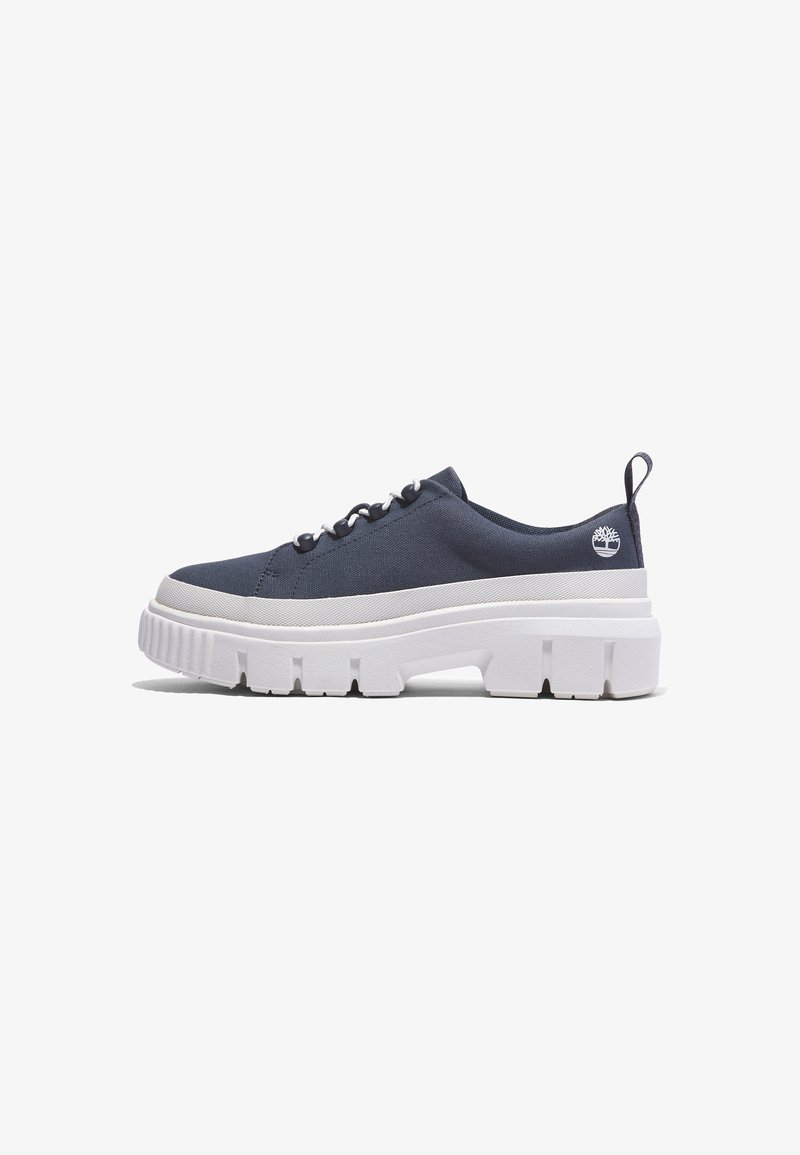 Baskets basses bleu marine avec une semelle épaisse blanche et volumineuse, fermeture à lacets, languette au talon et un petit logo d'arbre près du talon.