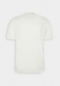 Tričko s krátkým rukávem a kulatým výstřihem v off-white, s měkkou texturou a bezšvovým designem ramene. Jednoduchý, minimalistický styl.