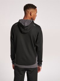 Svart atletisk hoodie med en grå mesh-fodrad huva, kontrasterande grå detaljer, långa ärmar och en figurnära design, sedd bakifrån.