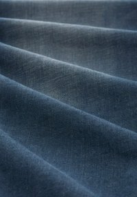 Sötétkék szövet, lágy textúrával, finom redőkkel és sima felülettel. Az anyag könnyűnek és enyhén fényesnek tűnik.