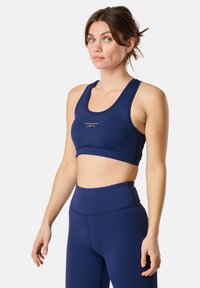 Granatowy stanik sportowy o gładkiej fakturze, z okrągłym dekoltem i szerokimi ramiączkami. Złote logo marki umieszczone na środku przodu.