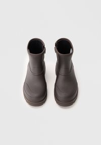 Botas de tobillo impermeables marrones con una textura suave, puntera redondeada, cierre de cremallera lateral y suela de contraste para mayor agarre.