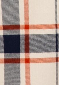 Tessuto a quadri con uno sfondo crema, caratterizzato da motivi a griglia blu scuro, arancione e rosso. La trama testurizzata aumenta la profondità visiva.